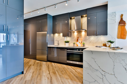 Modern kitchen with grey cabinets, marble countertops, and light wood flooring