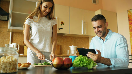 Couple preparing food and using tablet in kitchen