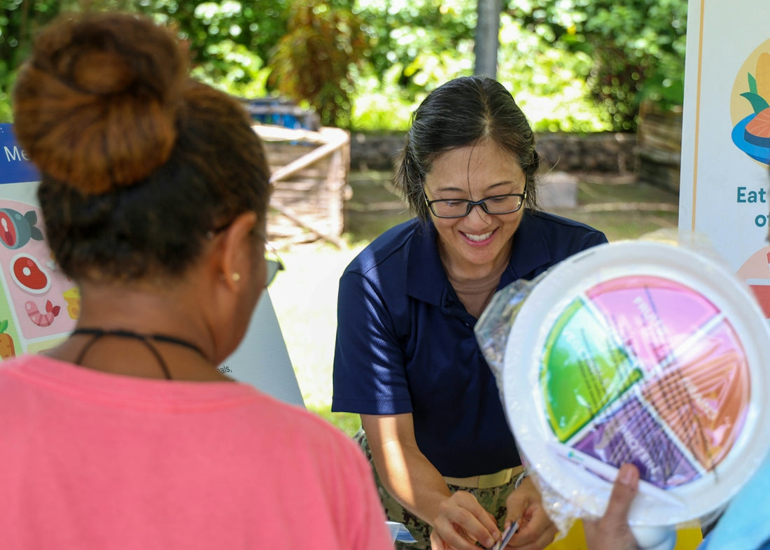 A woman shows a colorful plate to another person