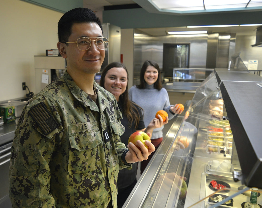 Man in uniform and two women holding fruit